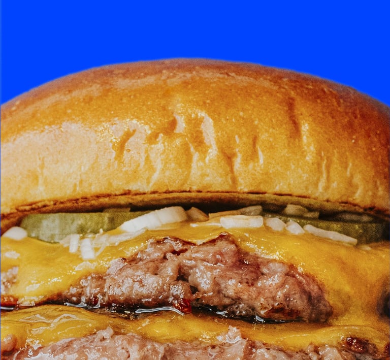 Primer pla d’hamburguesa doble de Flipa amb carn, cheddar fos, ceba i cogombrets