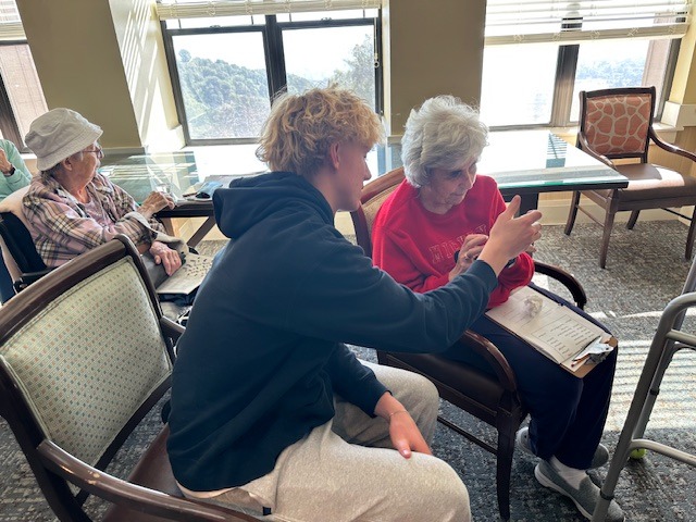 boy helping elderly woman learn how to add a new app on with her iphone