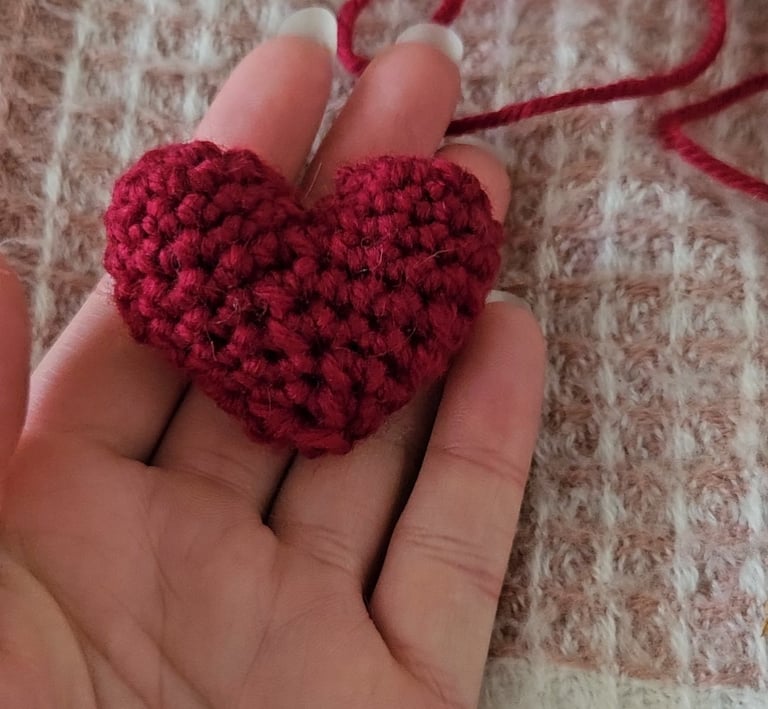 a red amigurumi heart in someones hand