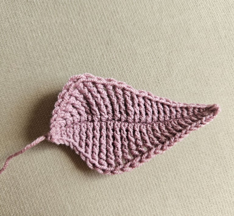 Handmade dusty rose crochet leaf applique featuring detailed texture on a neutral background.