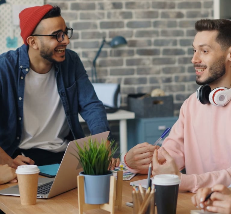 Diverse creative team collaborating and laughing during a brainstorming meeting in a modern office.