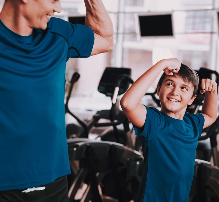 Un adulto e un bambino in palestra che mostrano i muscoli in modo giocoso, creando un momento divertente e motivante durante