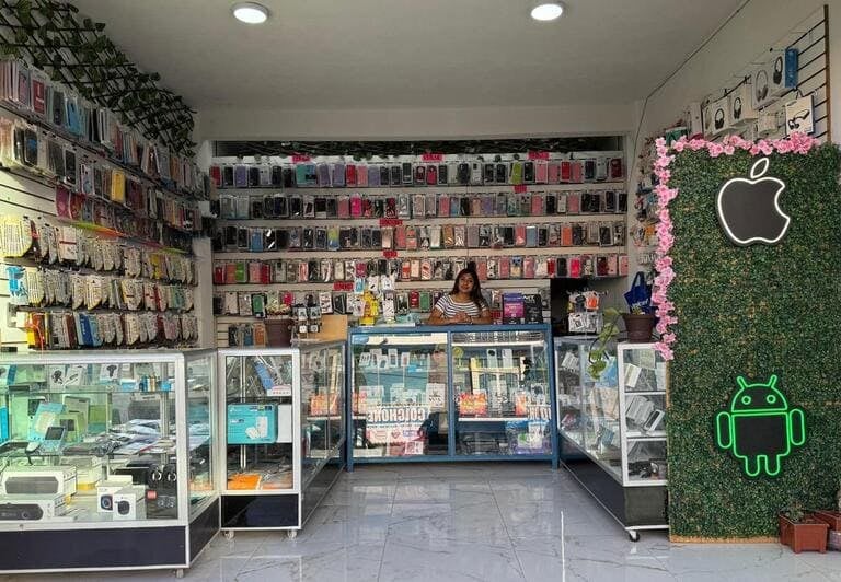 Interior de una tienda de reparación de celulares con estanterías de fundas coloridas y vitrinas de 