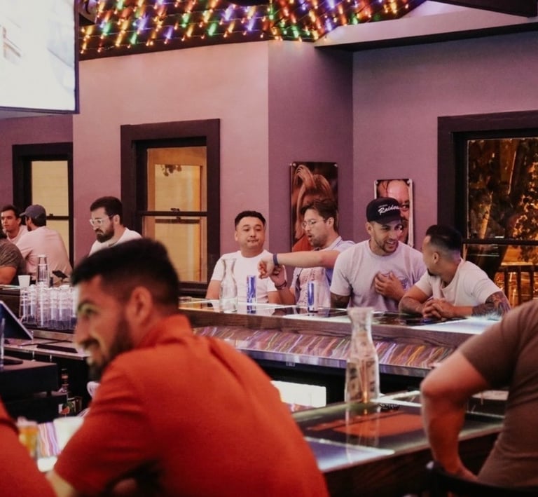 A group of friends socializing at a busy sports bar with neon lights and TV screens.