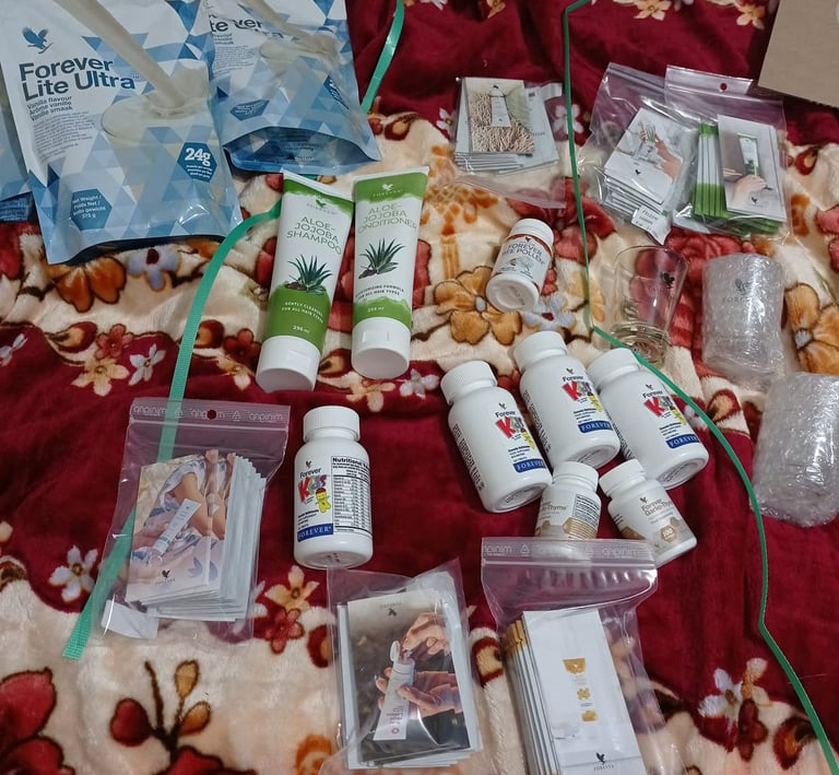 A collection of Forever Living health and beauty products, including Aloe Jojoba shampoo and Lite Ultra protein powder.