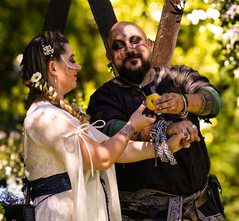 Pareja en ceremonia de boda medieval sonriendo y compartiendo un objeto amarillo en un bosque