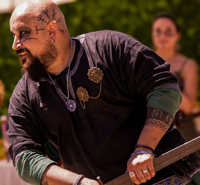 Hombre barbudo con tatuajes en el brazo sosteniendo una espada durante una celebración de boda temát
