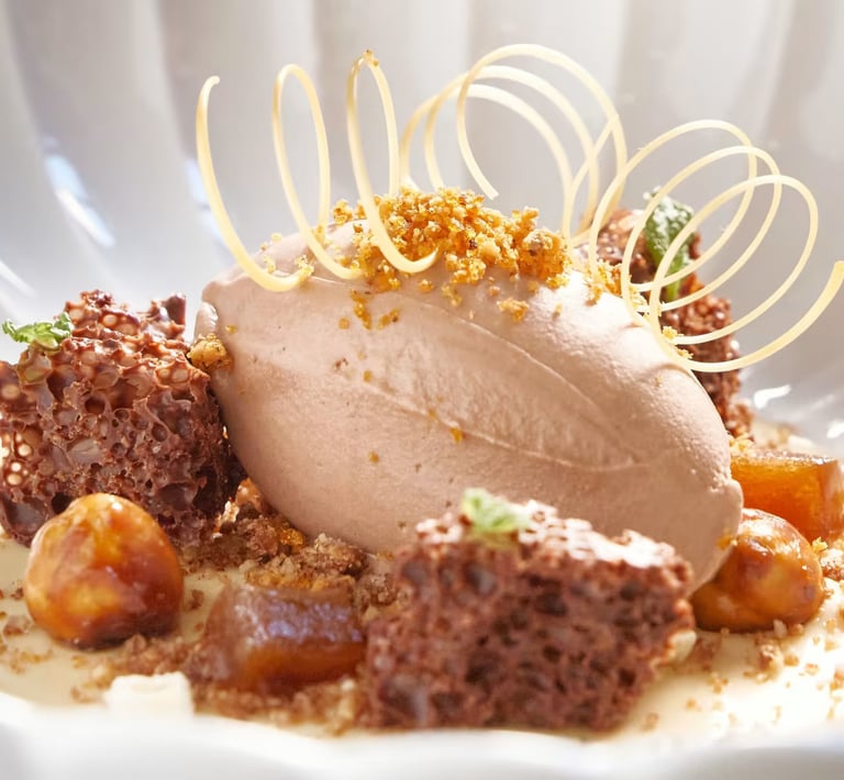 Plated dessert with chocolate ice cream, honeycomb, and caramel garnish.