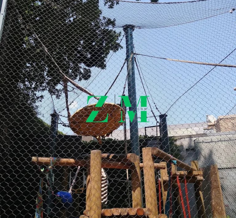 Outdoor ropes course with wooden climbing structures and safety netting for adventure activities.