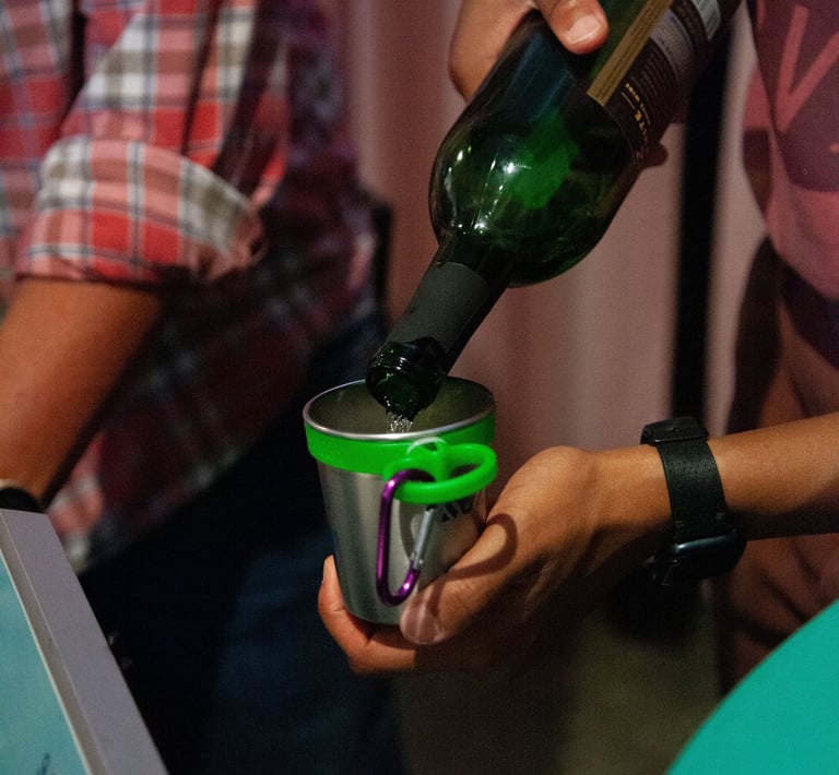 Hands pouring white wine into a small cup