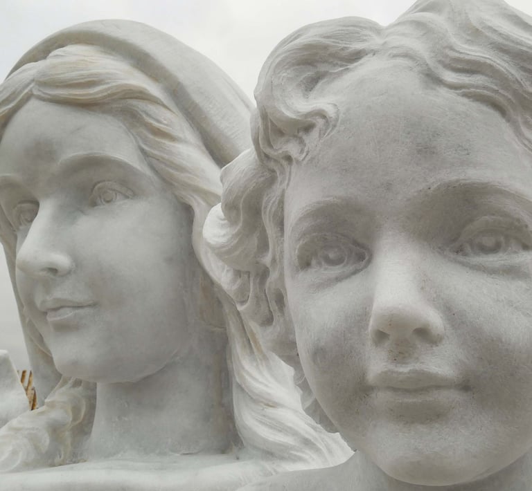Close-up of a white marble religious statue depicting a woman and child with serene expressions.