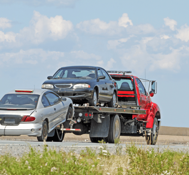A Surrey tow truck carrying a car with a flat bed