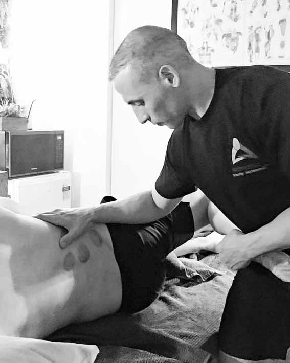 Male massage therapist performing Myofascial Stretching of the leg and back massage