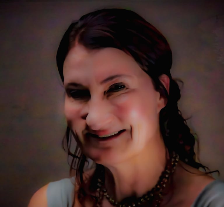 A smiling woman with dark hair and a beaded necklace in a professional headshot portrait.