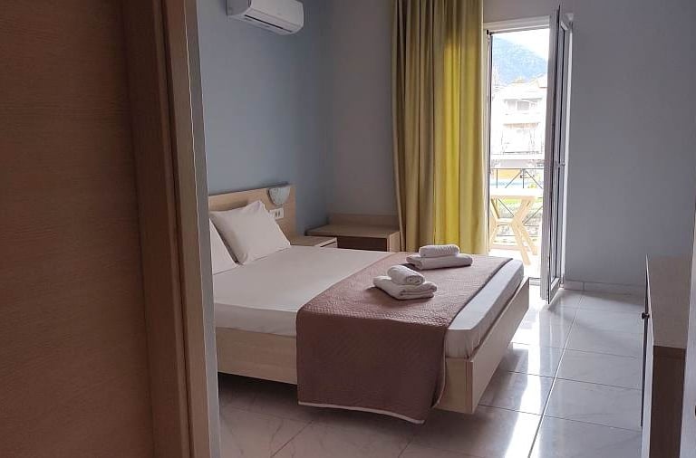 Delfini hotel bedroom with a bed and a balcony