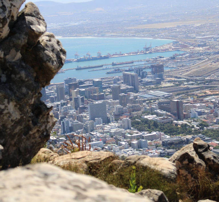 a boulder in the foreground, with a cityscape in the distance, far below the photographer's height