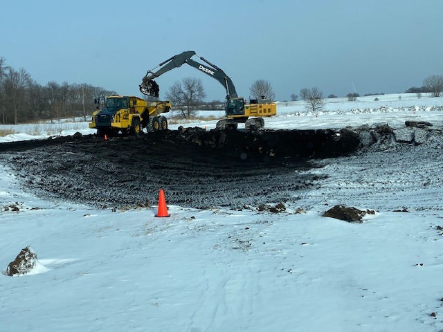 John Deere excavating pond in winter