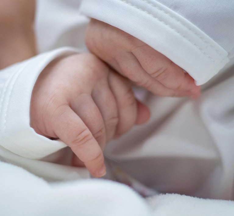 a baby's hand holding a finger on a white blanket