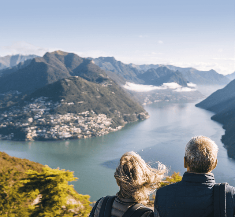 a couple of people sitting on a bench looking at the view of a lake