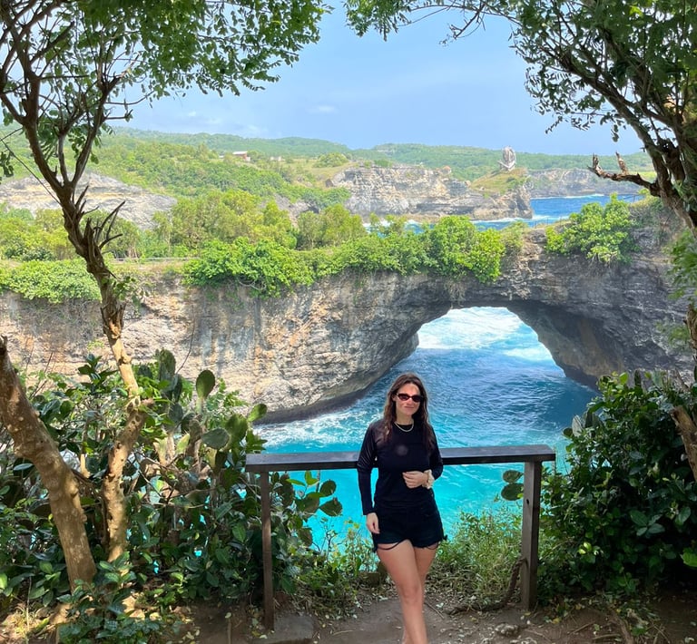 A woman stands before the scenic Broken Beach natural bridge arch in Nusa Penida, Bali.
