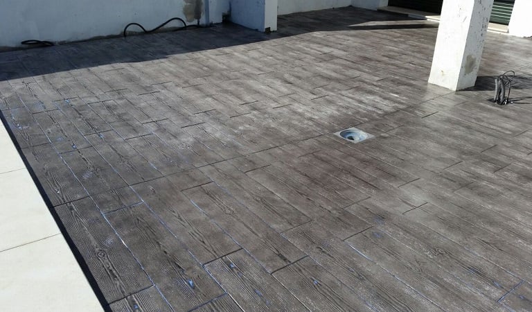 Superficie de hormigón impreso con acabado de imitación madera, perfecta para terrazas y exteriores modernos.