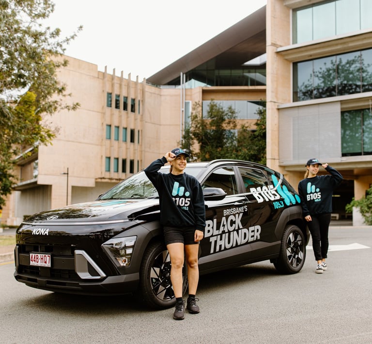 a woman from B105 standing next to a Hyundai Kona with a man in a black shirt