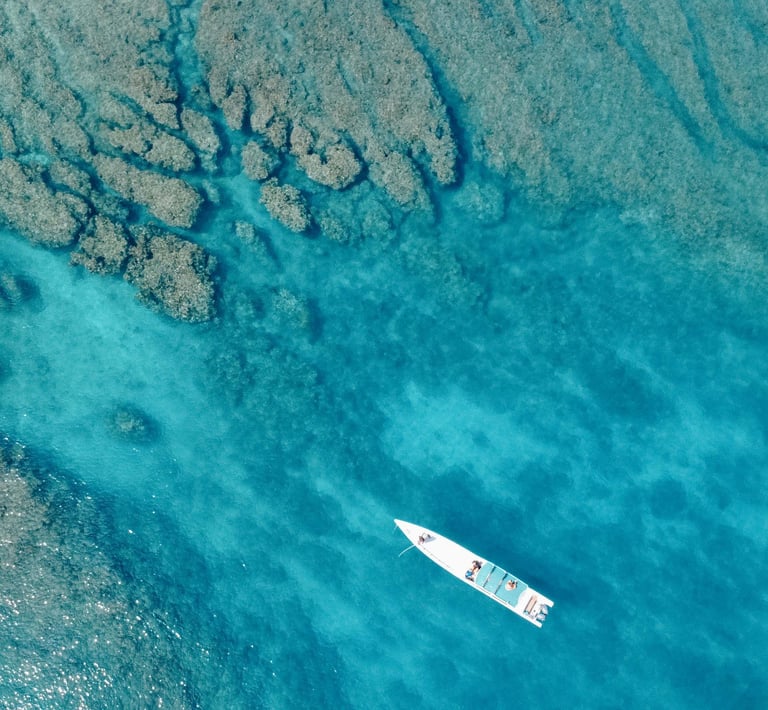 erial view of a surf boat floating above crystal-clear reef in the Mentawai Islands.