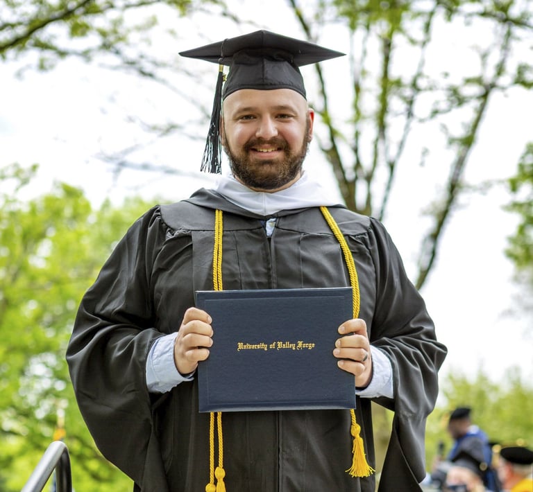 a man in a graduation gown holding a diploma