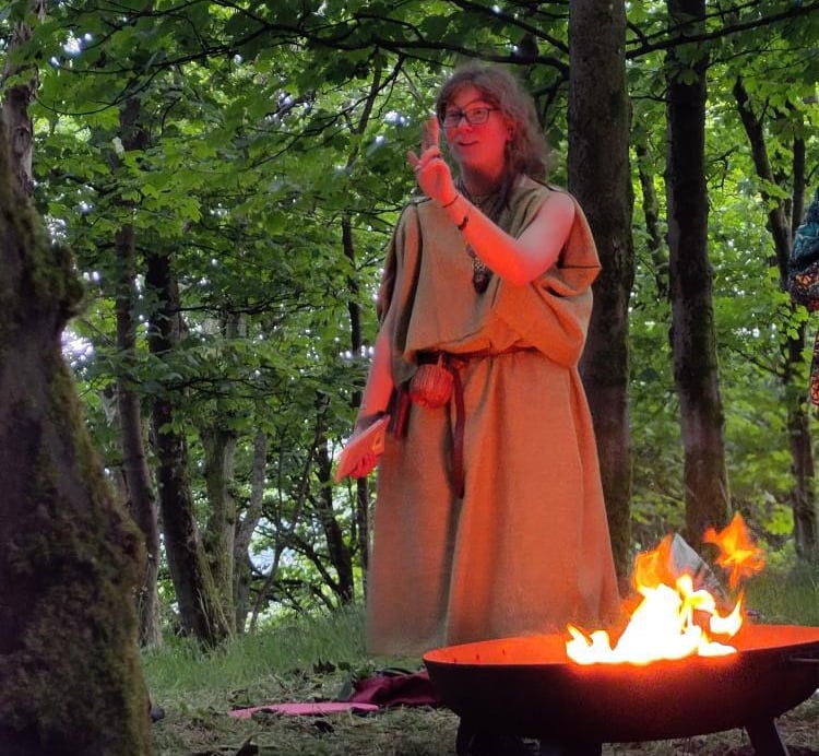 a woman in a robe is standing in front of a fire pit