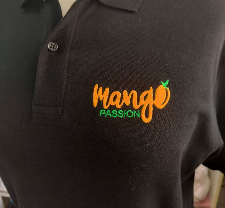 A black polo shirt featuring an embroidered orange and green Mango Passion logo on the chest.