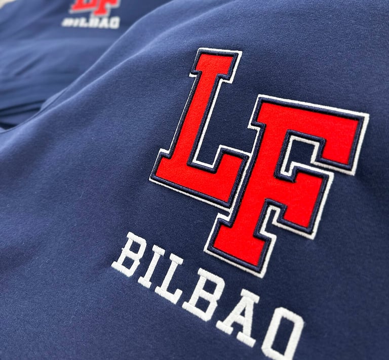Close-up of a navy blue hoodie featuring a red and white embroidered LF Bilbao varsity logo.
