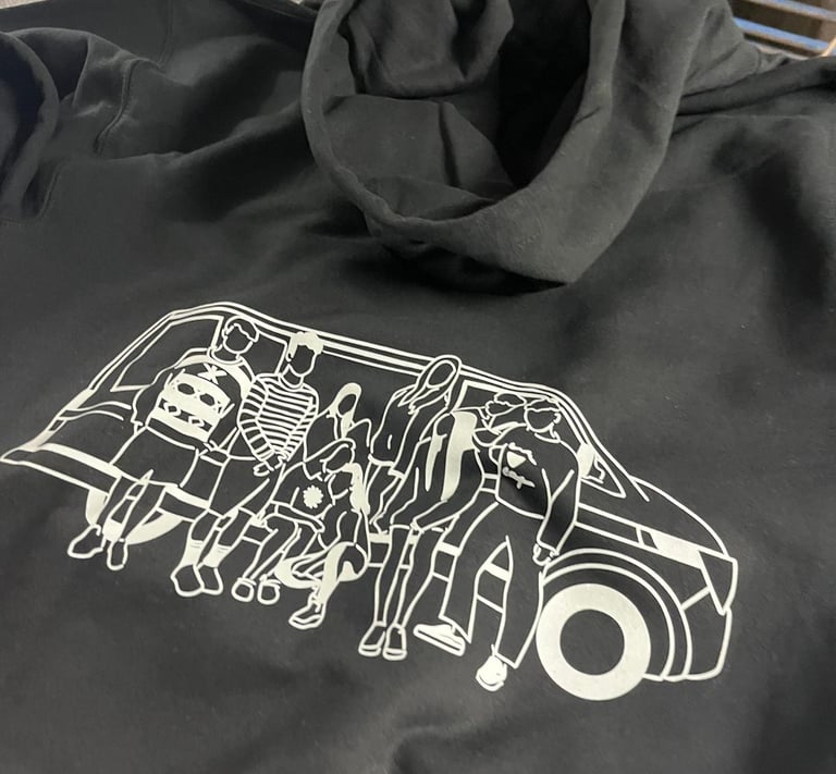 Black oversized hoodie with a white screen-printed graphic of a group of friends sitting on a van.