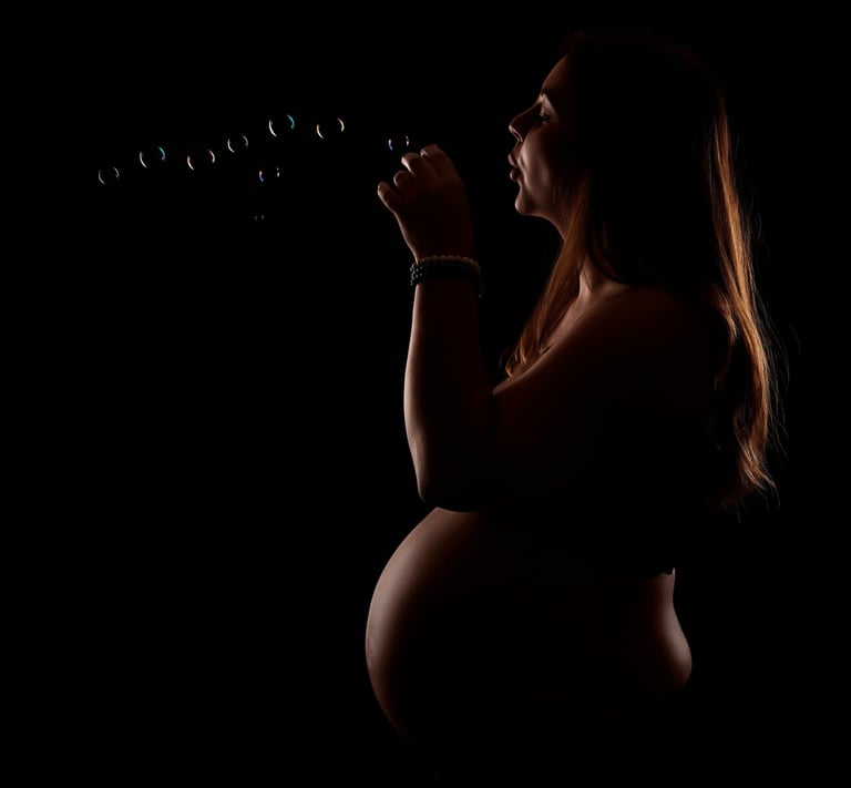 a pregnant woman blowing bubbles in the dark