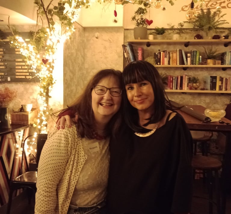 two woman have their arms around each other. They are smiling. They are at a Traitors themed party.