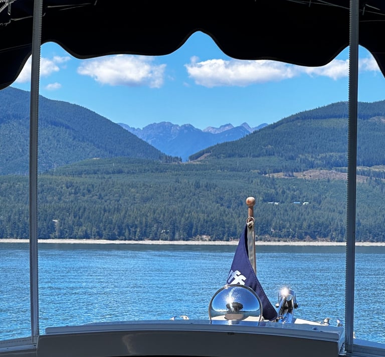front of boat with flag on pristine water facing majestic mountains