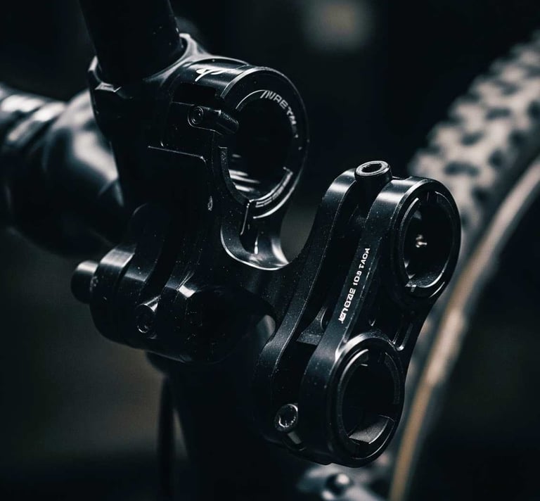 A close-up, darkly lit photograph of specialized bike mounts, crafted from dark, possibly anodized metal. The focus is on the