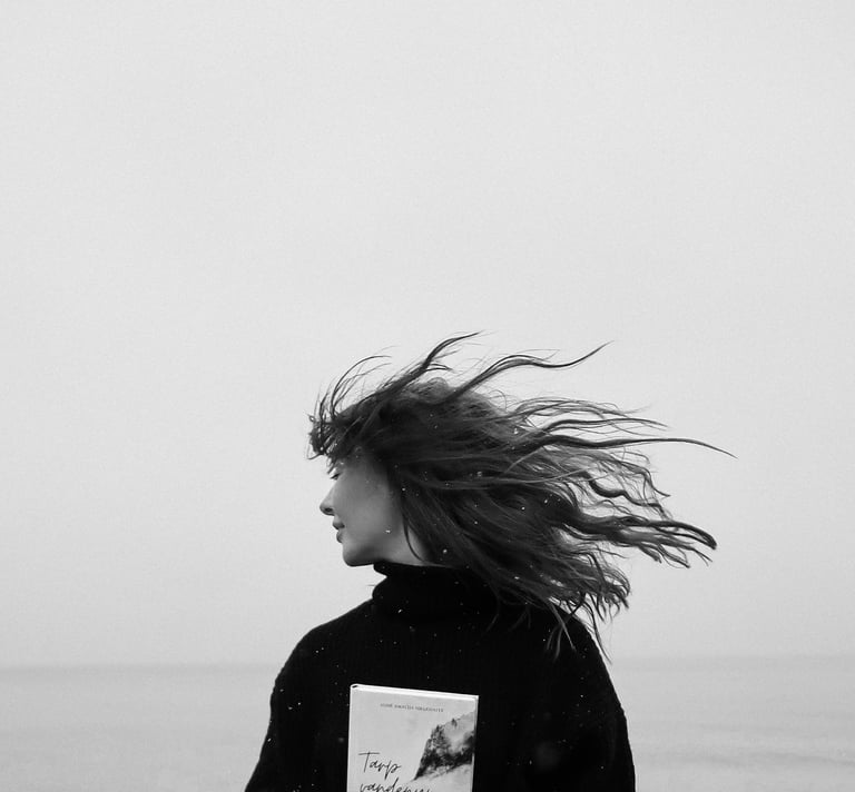 a woman standing on a beach holding a book