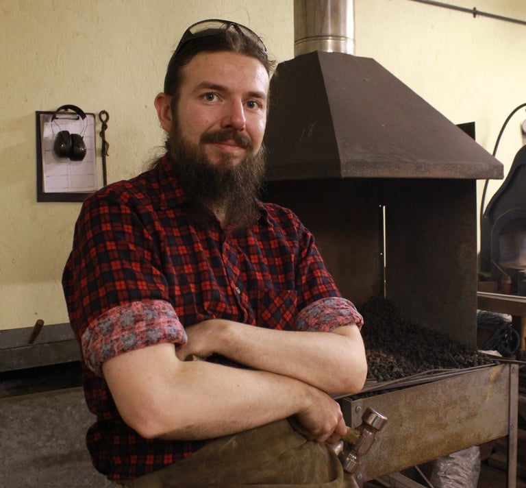 sexy bearded blacksmith with his arm crossed looking dahing in forge 