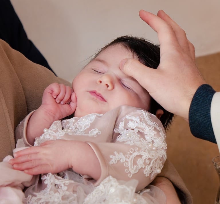 majka drži bebu u svojim rukama za vrijeme obreda krštenja