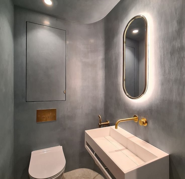 A modern bathroom with walls finished in blue Venetian microcement, a white trough-shaped washbasin