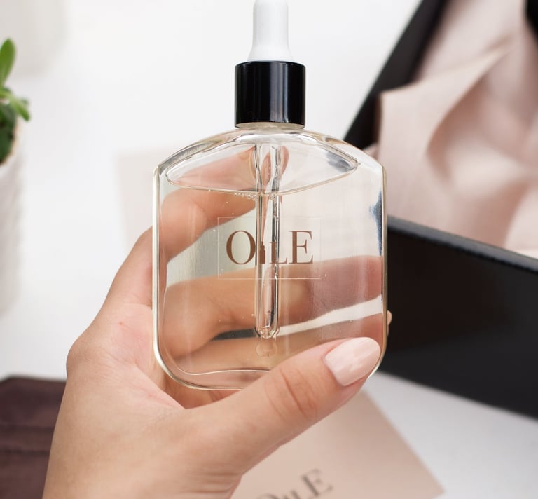 Hand holding a glass bottle of facial oil with a dropper against a minimalist aesthetic background.