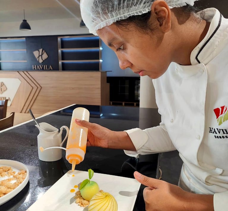a chef in a white uniform is pouring a sauce on a plate