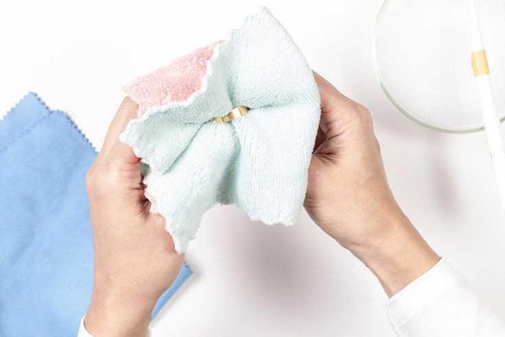 Manos utilizando un paño de microfibra suave para limpiar y pulir joyería