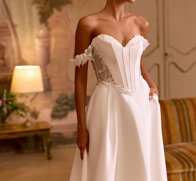Elegant bride in a strapless corset wedding dress with off-the-shoulder lace sleeves and a full satin skirt.