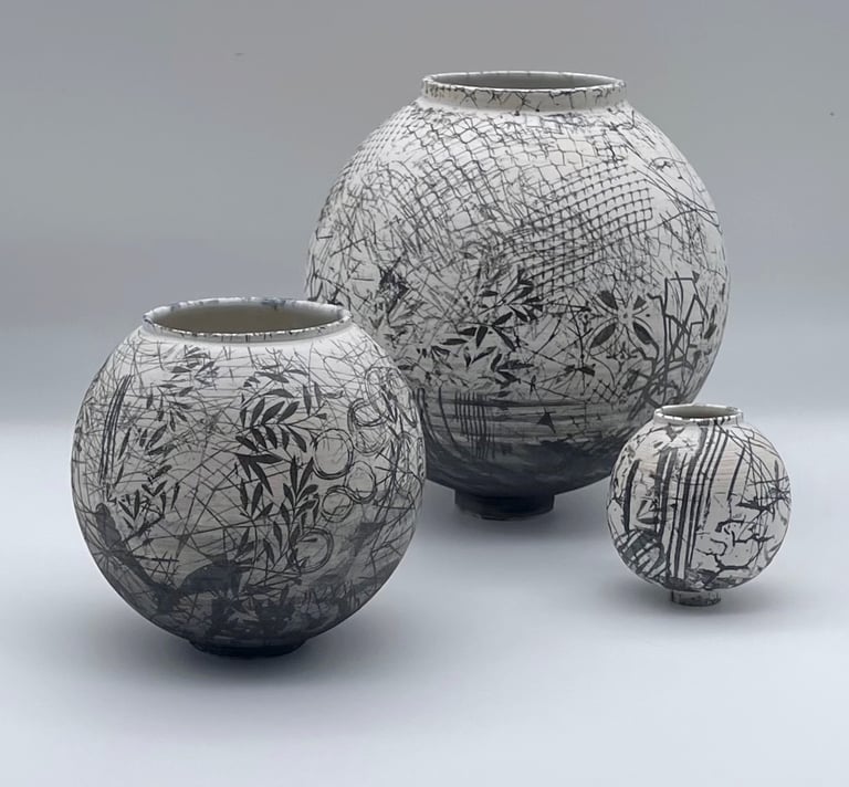 3 ceramic moon jars which are different sizes with abstract black and white pattern on the surface