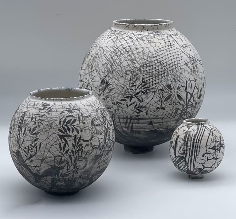 3 ceramic moon jars which are different sizes with abstract black and white pattern on the surface