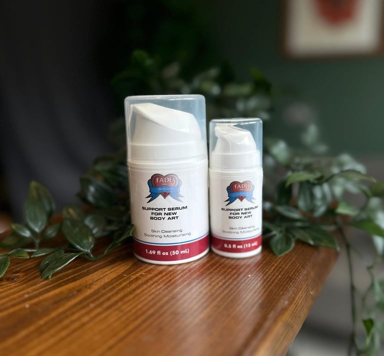 Two bottles of Fade The Heat aftercare support serum for new body art on a wooden table.
