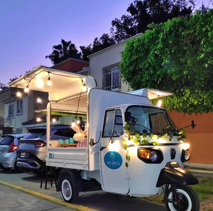 Piaggio italiano convertido en food truck con servicio de barra móvil de bebidas, en evento de noche