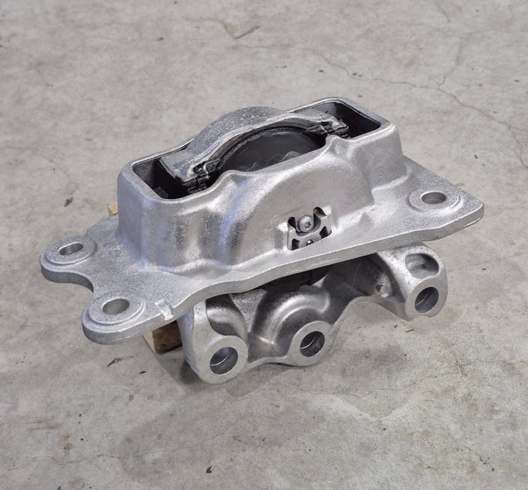 Durable silver metal engine mount replacement part for vehicle vibration control on a concrete floor.