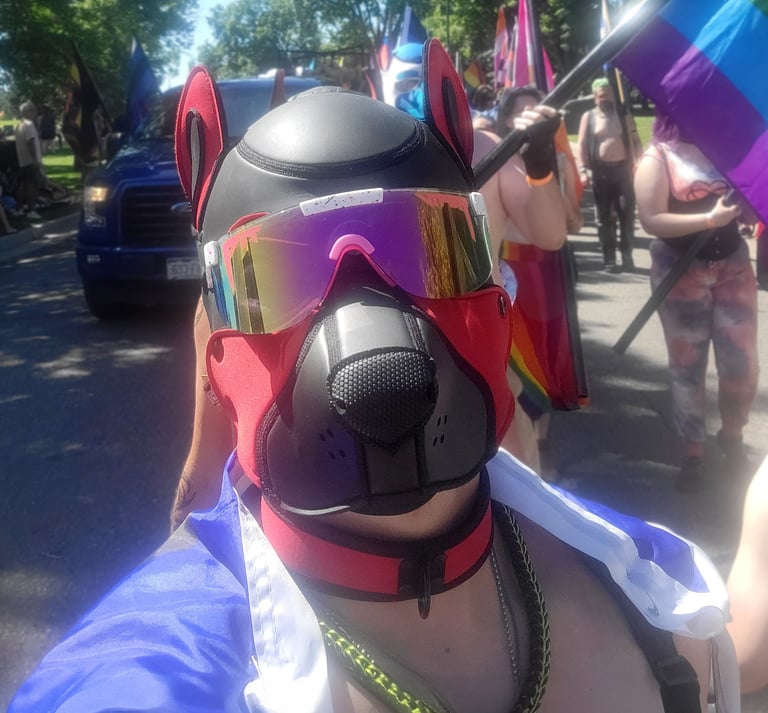 A man marching in a Pride parade wearing a pup mask.